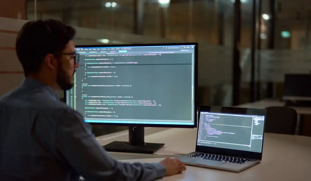 busy business man software developer working late on computer in dark office.